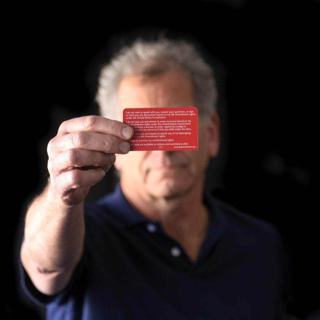 A man holding a know-your-rights red card.