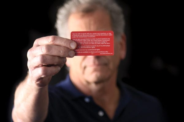 A man holding holding a know-your-rights red card