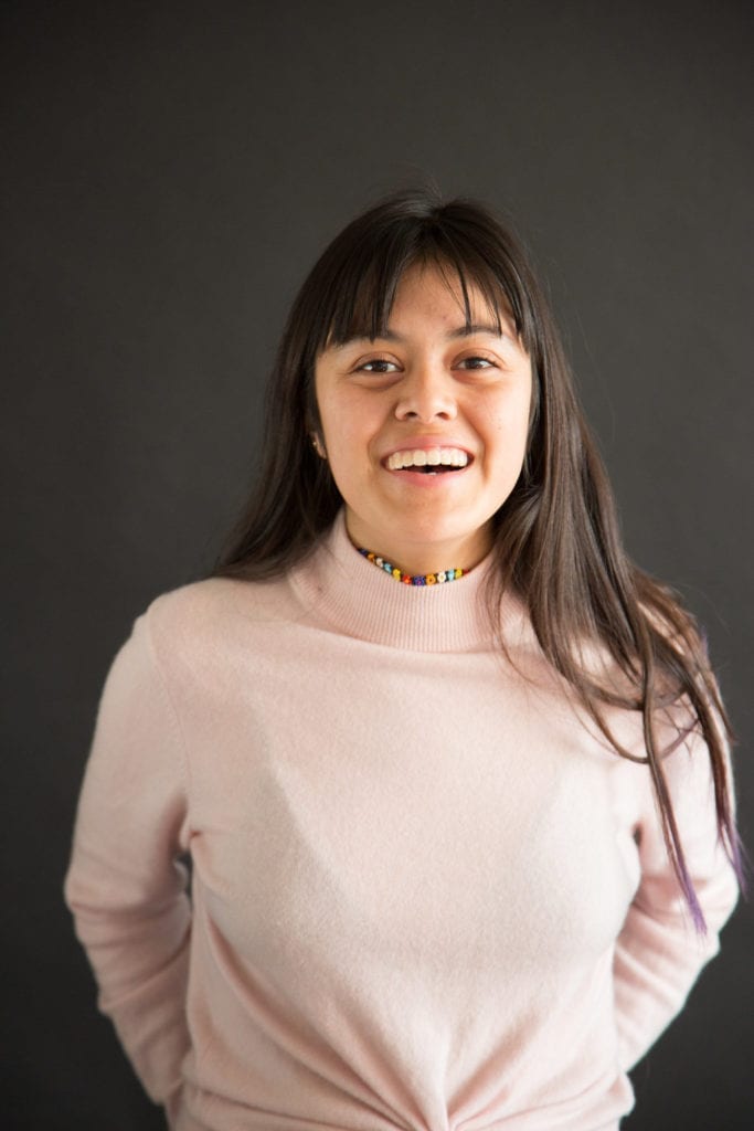 Young Latino woman wearing pink shirt smiling at the camera