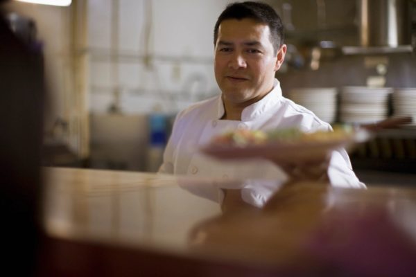 Young Latino man holding plate of food; cook