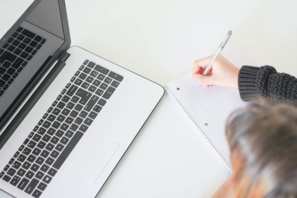 Woman at the computer writing on notebook