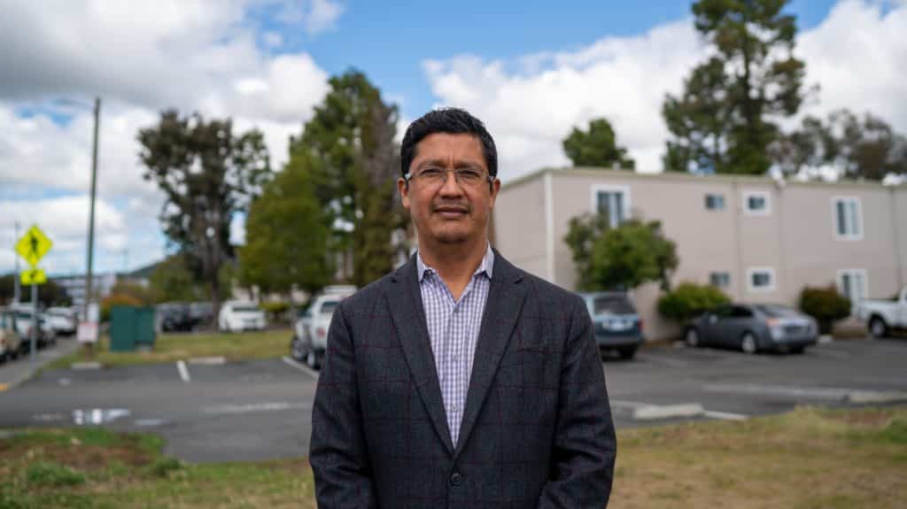 Omar Carrera, Canal Alliance CEO, standing in front of an apartment building.