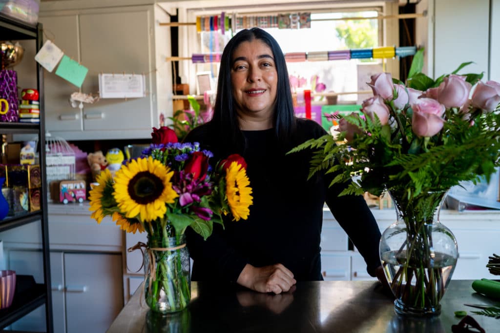 Iris Y Deleon poses in front of her flowers at her garage.