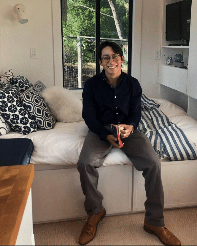 Melkyn Mazariegos poses in his bedroom with a book in his hand.